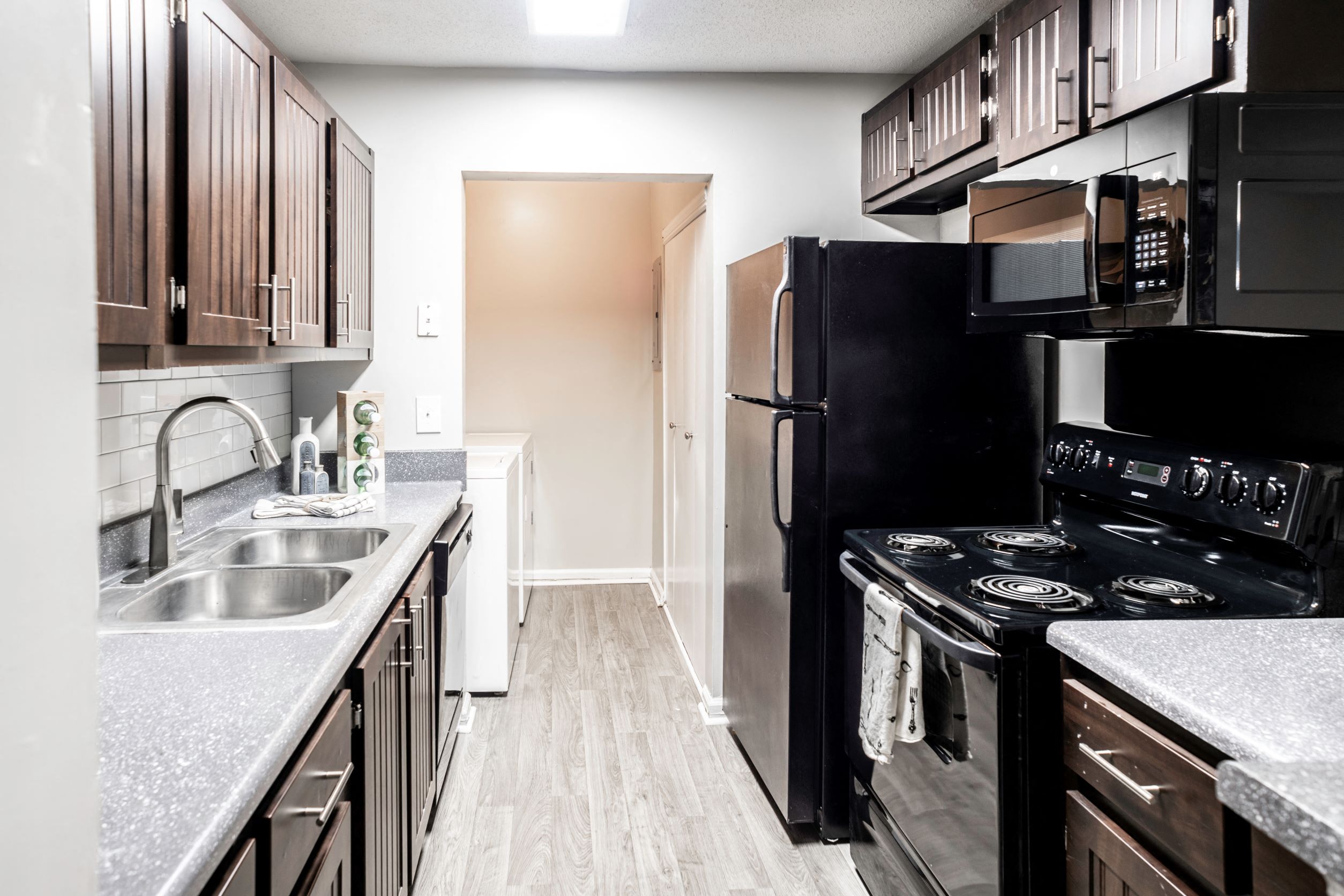 Galley kitchen with black appliances located at Addison on Cobblestone located in Fayetteville, GA 30215